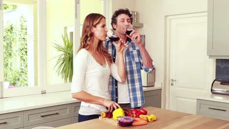 Happy-couple-slicing-vegetables-and-drinking-wine