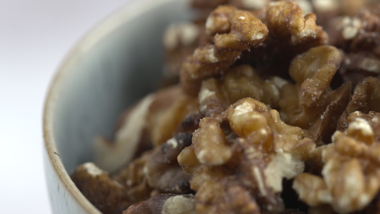 Noci. Primo piano macro 4K di noci che ruotano. Noci che girano in una ciotola. Alimento vegano crudo a base vegetale ricco di proteine. Cibi sani e vegetariani. Ingredienti per una colazione sana. Ripresa macro 4K.