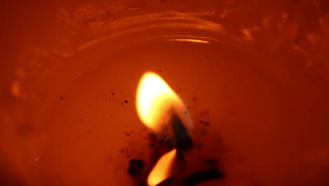 very close view of an orange, red candle with melted wax insde the crate, blurring until becomes an abstract moving bulb of light