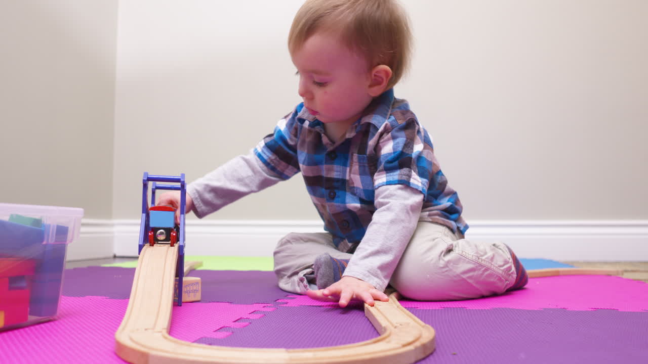 Baby boy pushing a toy train down the track
