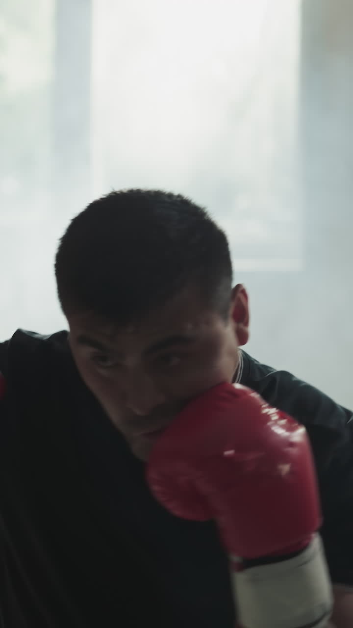 Athlete does punches and block training in sports club. Skilled sportsman beats punching bag in equipped gym against dust cloud slow motion. Martial arts champion
