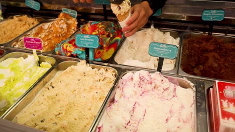 person scooping ice cream into a cone