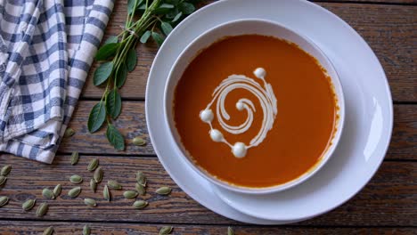 warm pumpkin soup is served in white bowls on a rustic wooden table, garnished with a creamy swirl and surrounded by fresh herbs and pumpkin seeds, creating an inviting autumnal scene