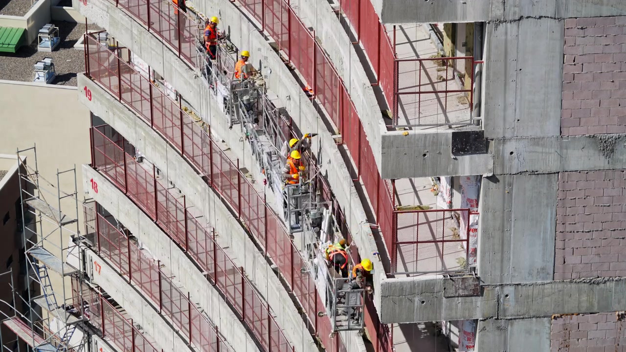 Construction Workers on Suspended Scaffolding Working on High-Rise Building Exterior