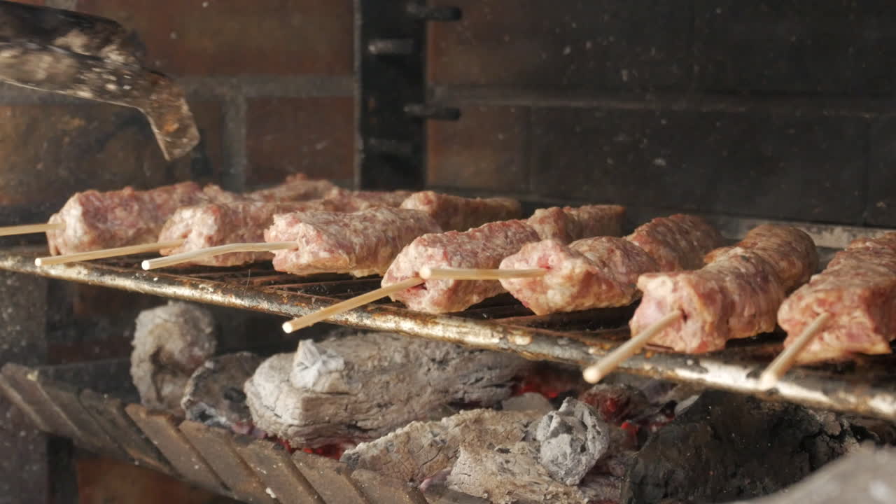 macro de un chef girando el kebab de carne rumano en la parrilla con una pinza