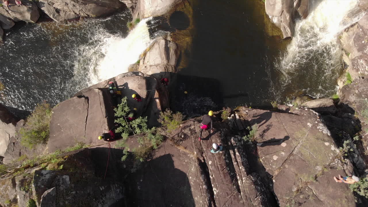 Aerail top view of people jumping into a river while doing canyoning.