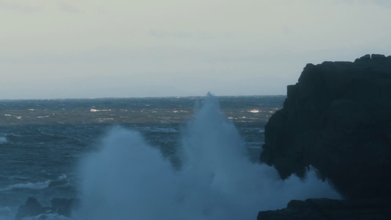 increíbles olas marinas rompiendo alto en el aire sobre las rocas en ultra cámara lenta durante la tormenta darragh viento clima amanecer. poderoso oleaje turbulento en la bahía británica 4k.