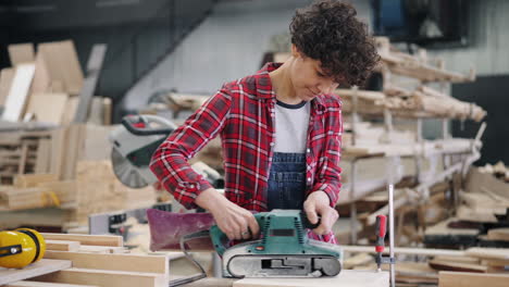 woman using belt sander in a workshop