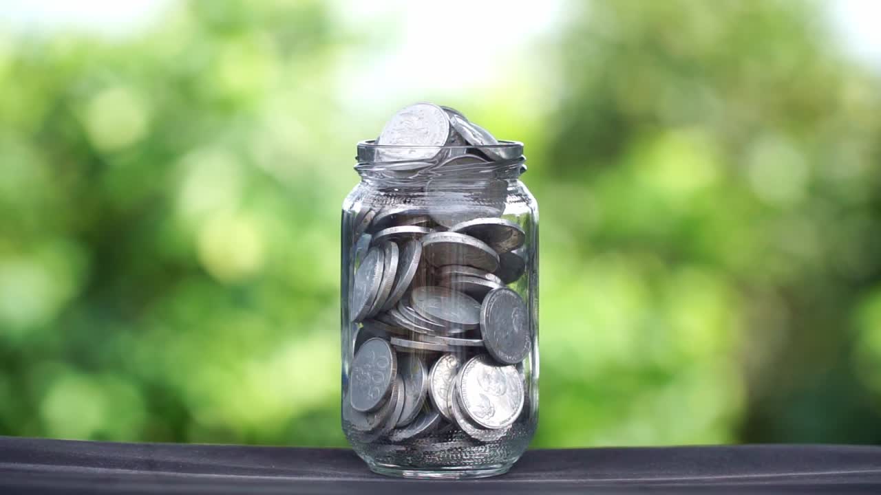 Full jar of money against green natural background, investment concept