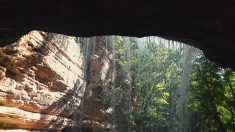 behind waterfall, trickling water, down rocky cliff ,tilt down