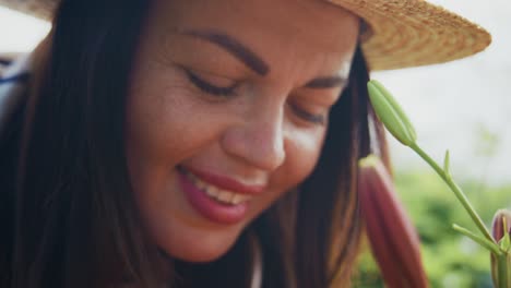 woman with long dark hair enjoying nature while smelling a vibrant flower in a sunny garden