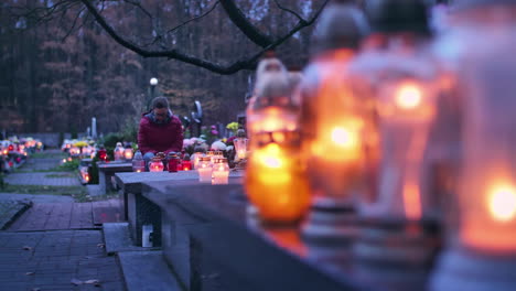 mujer sentada en una tumba alrededor de velas encendidas