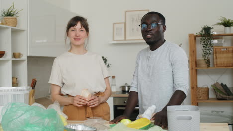 young multiethnic couple posing for camera while sorting waste