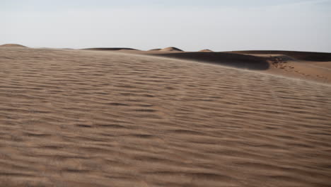 arena en cámara lenta soplando a través del paisaje desértico del medio oriente cerca de dubai en los emiratos árabes unidos