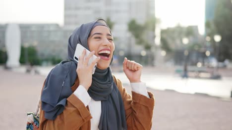 excited woman in hijab celebrates good news on a phone call in an urban setting