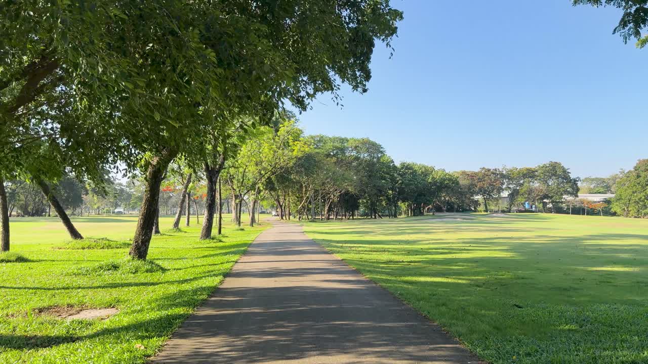Una fluida panoramica della telecamera segue un sentiero asfaltato attraverso un lussureggiante campo da golf tropicale verde.