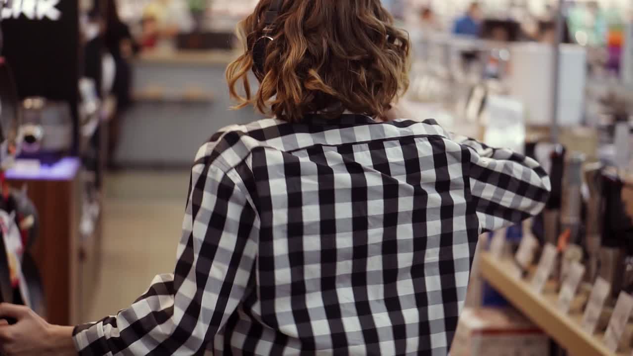 rara vista de una linda mujer joven caucásica con cabello corto y rizado y con auriculares bailando y escuchando música en el medio