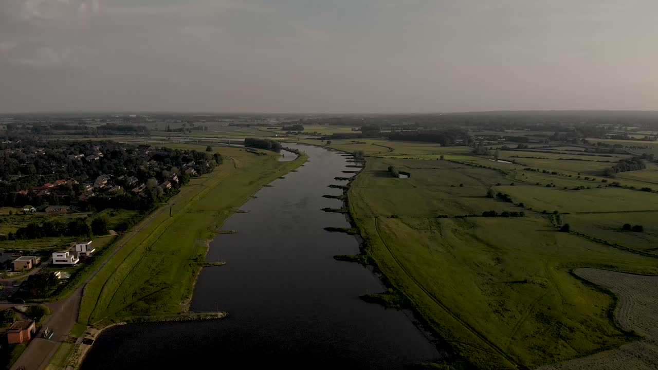 흐린 날에 네덜란드 한자 중세 탑 마을 zutphen의 범람원을 보여주는 천천히 뒤로 이동하는 강 ijssel을 따라가는 일몰 공중 도시 경관