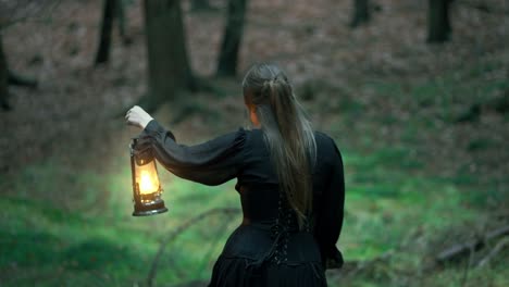 ein mädchen mit langen haaren und einem schwarzen kleid geht mit einer lampe in der hand durch einen dunklen wald