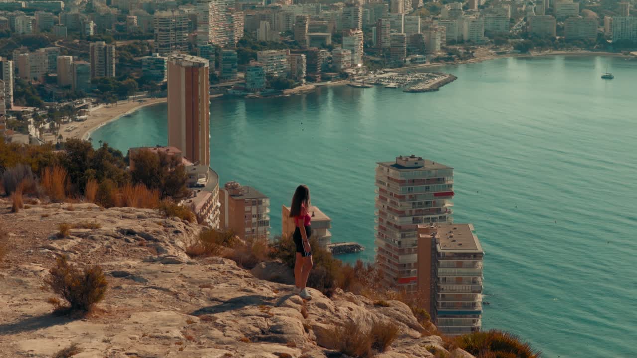 Viaggio di una donna che guarda il Mar Mediterraneo e la città dalla cima di una montagna