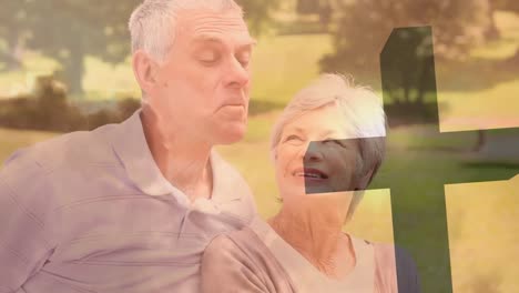 animation of caucasian senior woman feeding strawberry to husband in park over silhouette cross