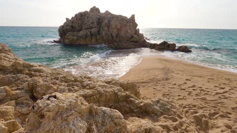 Hermosa-Playa-De-Arena-Mediterránea,-Maresme-Barcelona,-San-Pol-De-Mar,-Con-Rocas-Y-Mar-Tranquilo-Y-Turquesa,-Costa-Brava