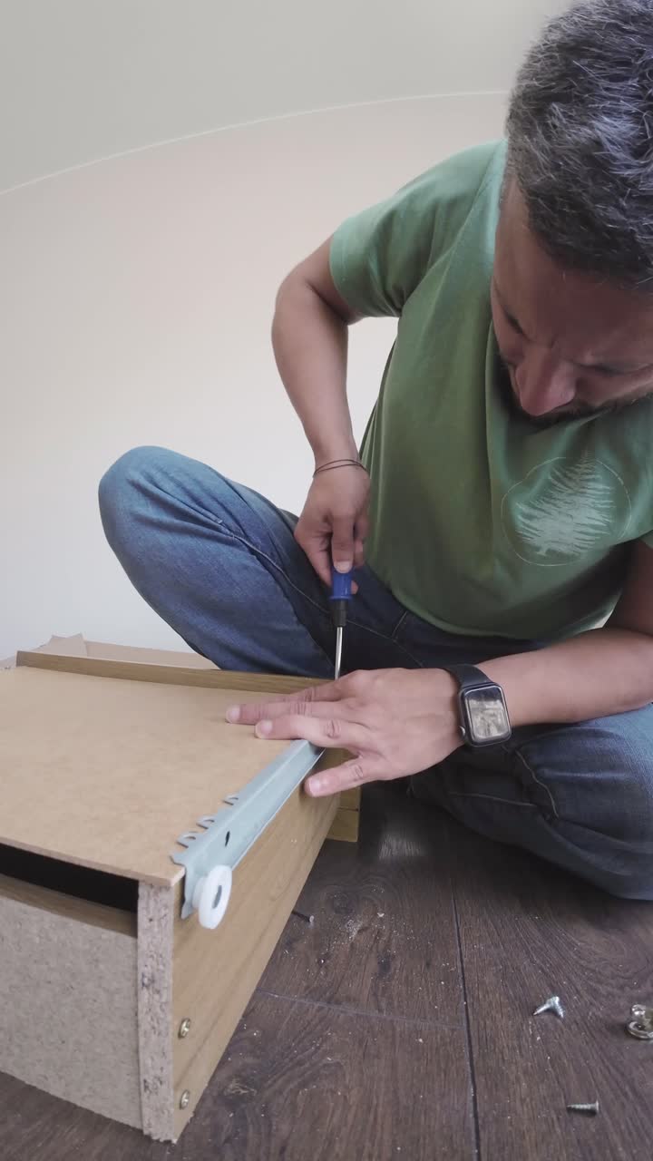 Uomo che assembla mobili in kit con un cacciavite.
