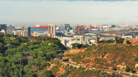 Cars-passing-road-pass-above-city.-Aerial-descending-footage-of-modern-city-borough-and-surrounding-landscape.-Cape-Town,-South-Africa