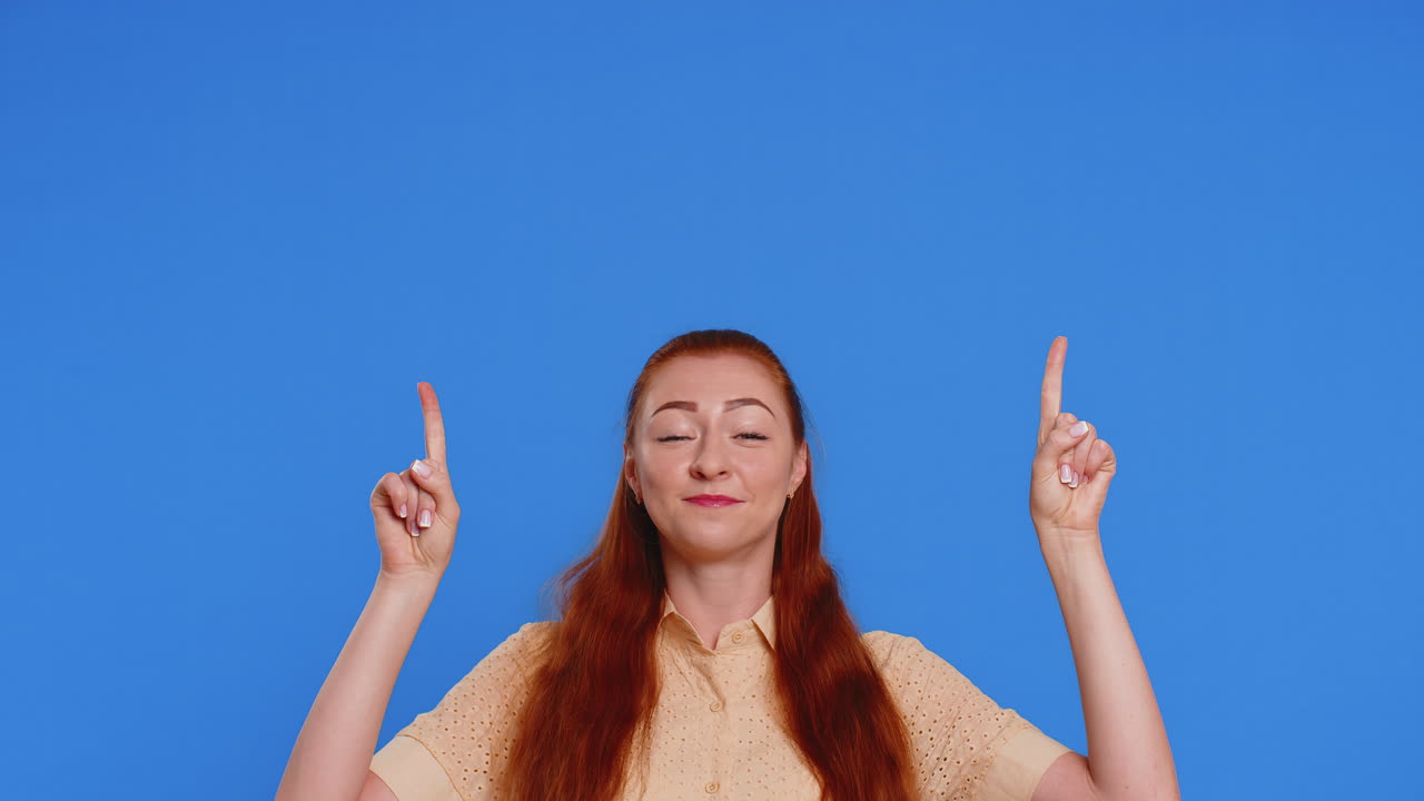 Adult woman showing thumbs up and pointing over head on blank space place for advertisement logo
