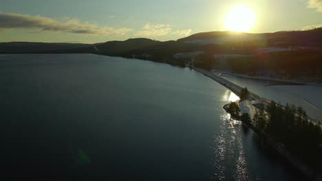 sunset, flying along the bridge at sea towards the forest, aerial