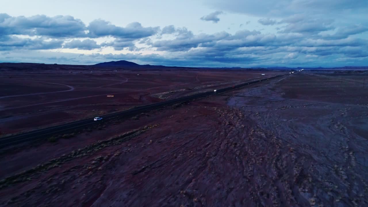 Lonely highway slicing through desert plain under stormy clouds, deep dusk hues