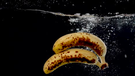 Ripe-bananas-being-dropped-into-water-in-slow-motion