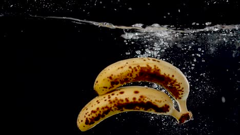 ripe bananas being dropped into water in slow motion