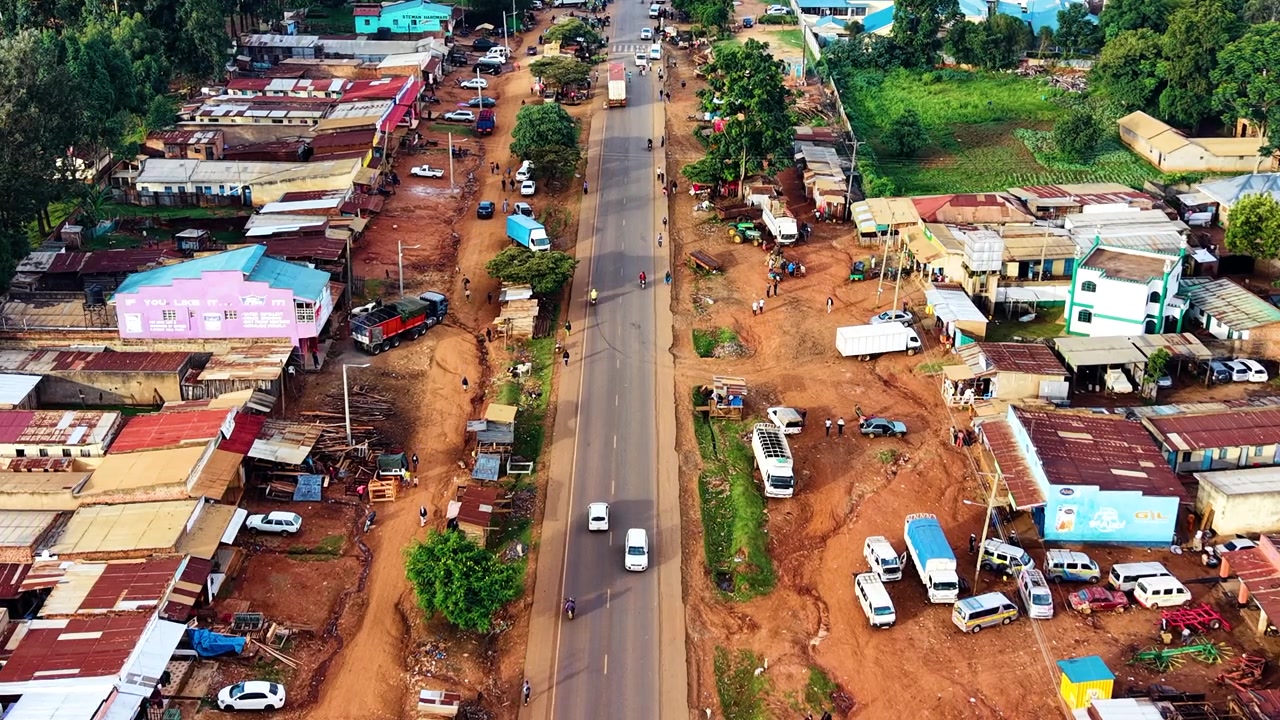 Strade del Kenya, strade rurali, insediamento rurale povero, strada danneggiata con drone che riprende veicoli sulla strada dall'alto