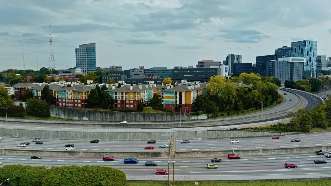 Aerial wide shot of colored houses in suburb neighborhood of american town. Traffic on american highway and Skyline in distance. Atlanta Town, Georgia., United States. Cloudy day over cityscape.