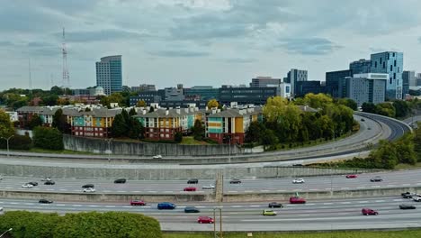 aerial wide shot of colored houses in suburb neighborhood of american town. traffic on american highway and skyline in distance. atlanta town, georgia., united states. cloudy day over cityscape.