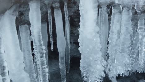 Waterfall-in-the-winter-season,-forming-ice-and-bubble-in-blue-and-cold-tones