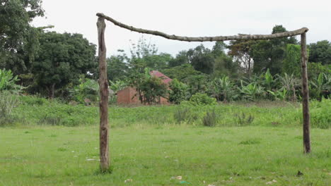 Rural-soccer-goal-on-a-grassy-field-with-trees-and-a-building-in-the-background