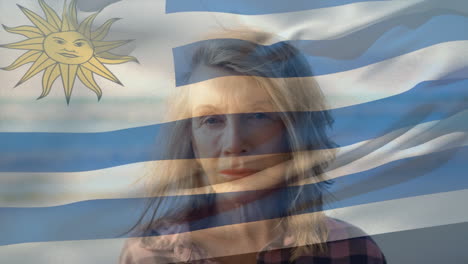 animation of flag of uruguay over sad senior caucasian woman on beach