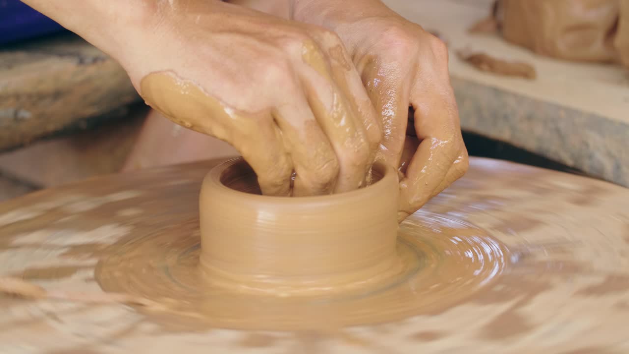 manos moldeando arcilla en una rueda de cerámica