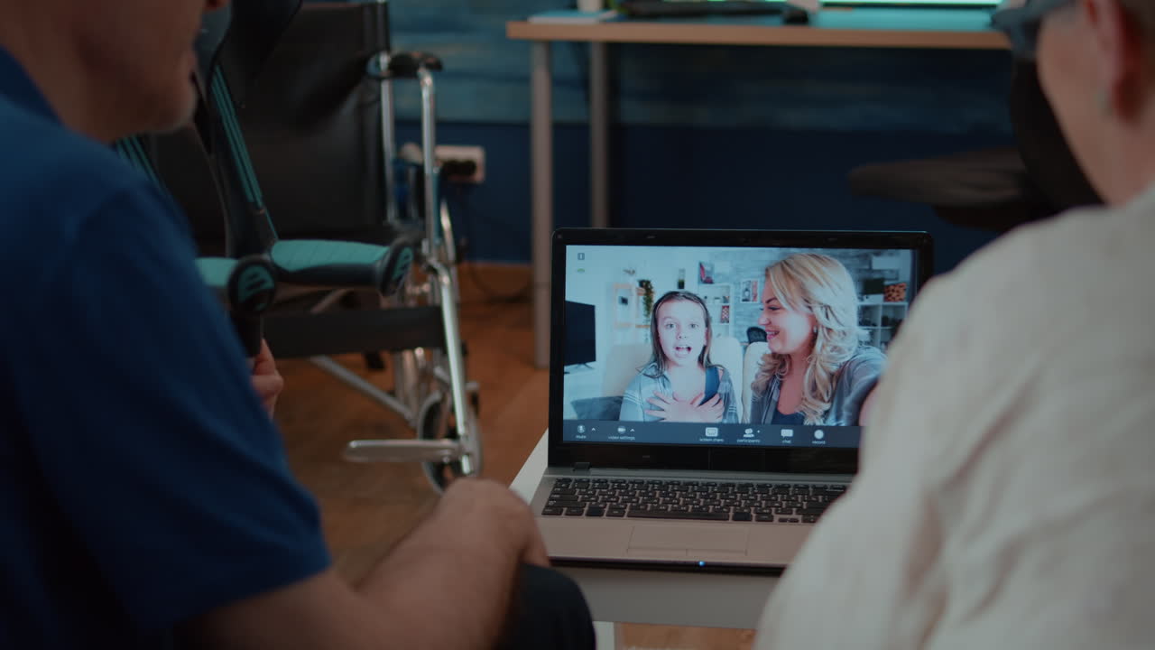 Seniors on a video call with family using a laptop at home