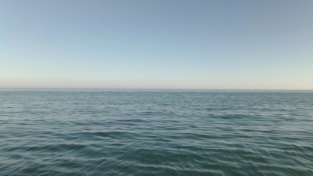 공중 풀백은 해안의 들쭉날쭉 한 바위 해변 위로 바다 파도를 진정시키는 낮은 모습을 보여줍니다.