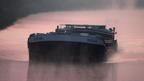 barge on rhine-herne canal sailing during sunrise with fog, medium shot