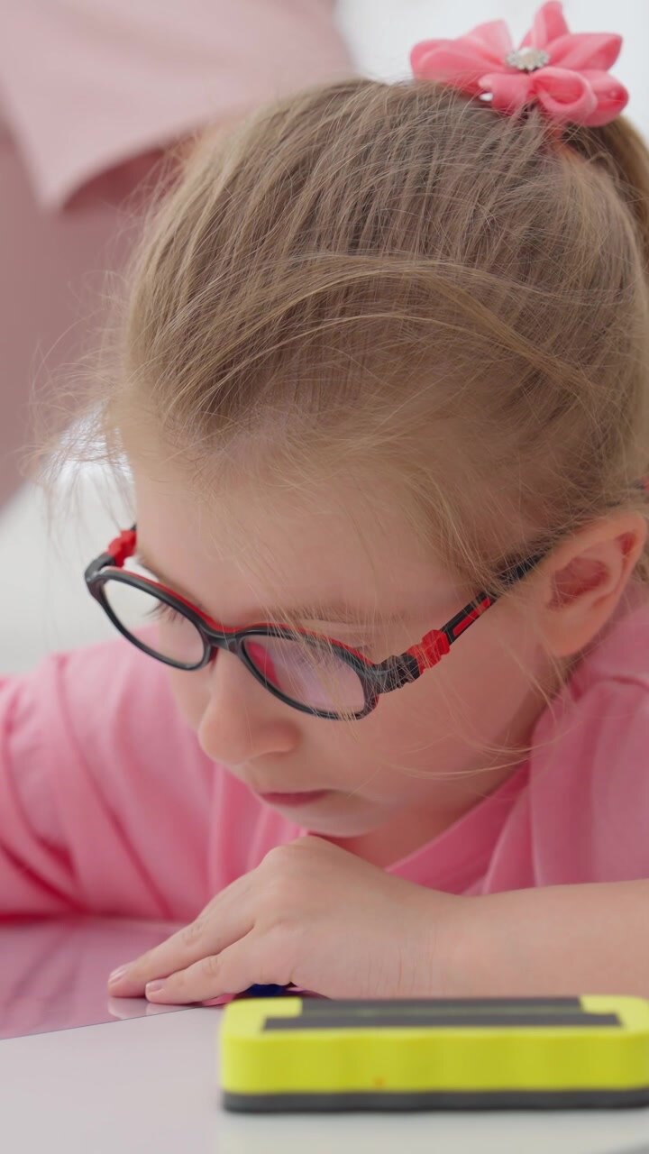 Bambina concentrata con gli occhiali che disegna con un pennarello