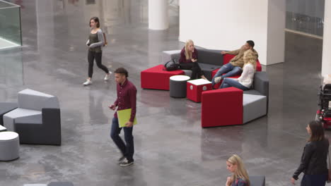 students relax together in the lobby of a busy university, shot on r3d