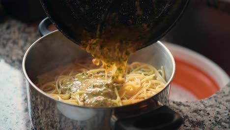 close up of a person serving a sauce over a pot of spaghetti