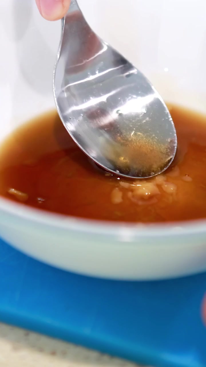 Primo piano di zucchero di palma che si scioglie nella salsa di pesce con un cucchiaio, in un ambiente cucina.