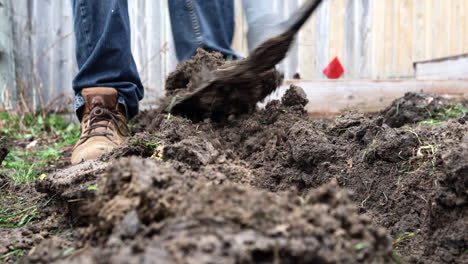 person with pickaxe mattock trenching soil in a garden yard