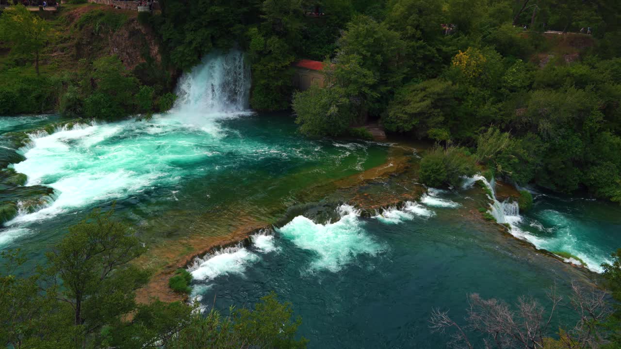 Crystal clear cascades surrounded by lush forest and historic mill in Krka National Park, Croatia