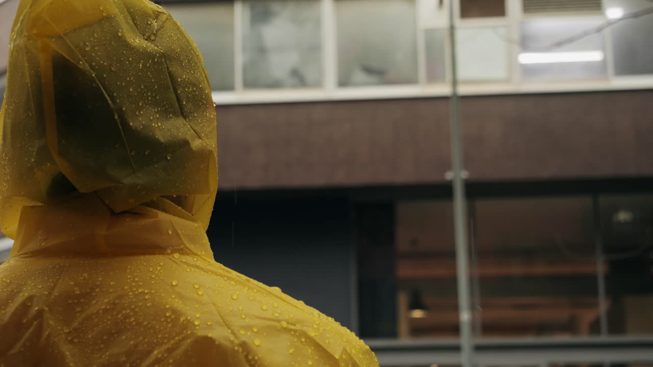 Business man tourist person with umbrella and raincoat on rainy european city street, lights reflecting, walking in Barcelona or Amsterdam during the rain